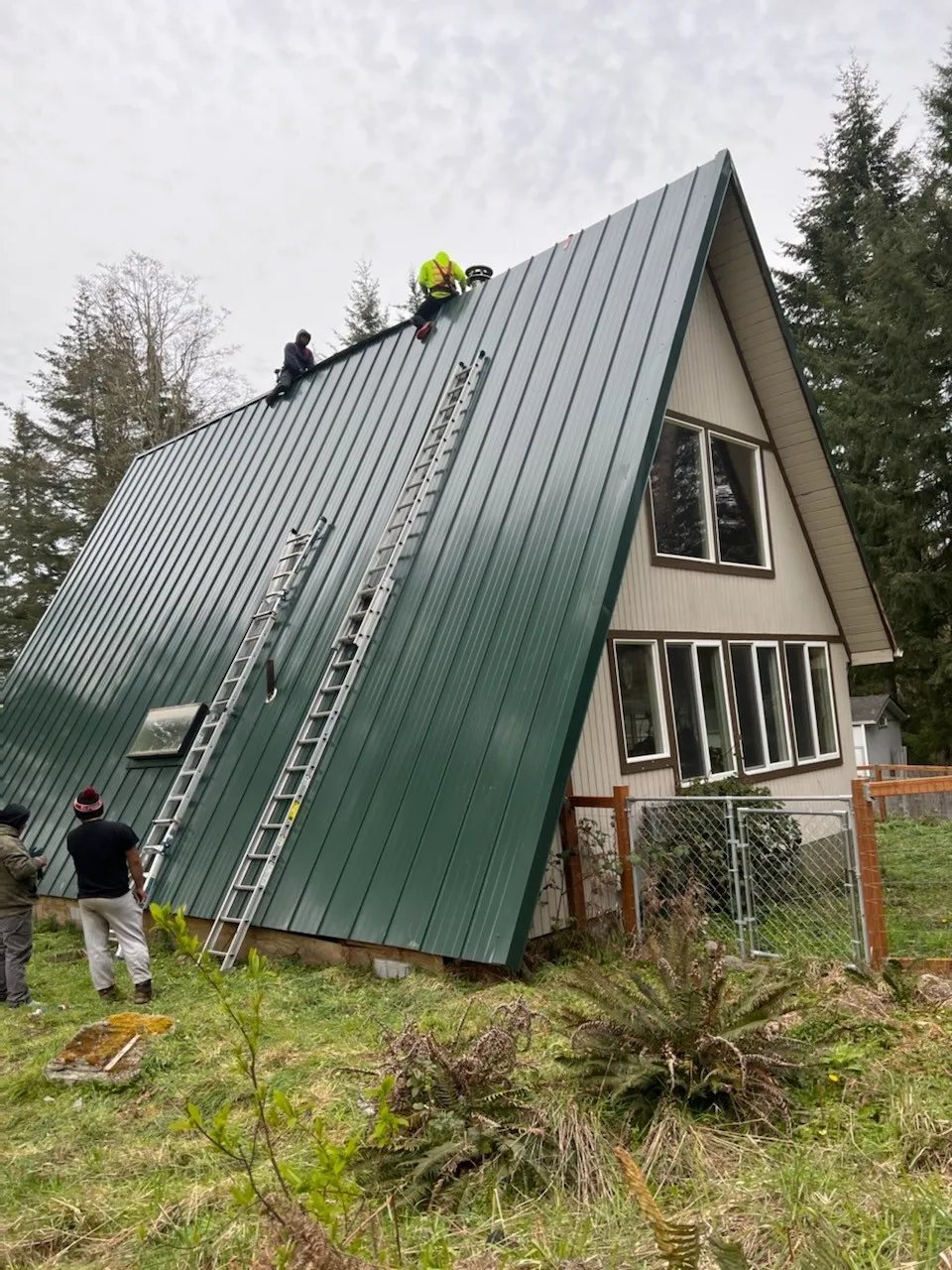 Mr. Roof crew installing a standing-seam metal roof on a steep A-frame home
